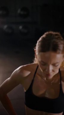Dikey. Güzel vücutlu bir kadın spor salonundaki ağır egzersizlerden dinleniyor. Güzel genç sporcu egzersizler arasında inanılmaz bir vücut gösterisi sergiliyor..