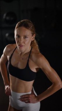 Dikey. Güzel vücutlu bir kadın spor salonundaki ağır egzersizlerden dinleniyor. Güzel genç sporcu egzersizler arasında inanılmaz bir vücut gösterisi sergiliyor..