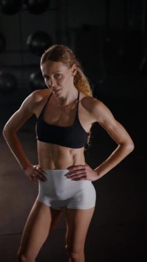 Dikey. Güzel vücutlu bir kadın spor salonundaki ağır egzersizlerden dinleniyor. Güzel genç sporcu egzersizler arasında inanılmaz bir vücut gösterisi sergiliyor..