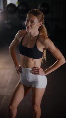 Dikey. Güzel vücutlu bir kadın spor salonundaki ağır egzersizlerden dinleniyor. Güzel genç sporcu egzersizler arasında inanılmaz bir vücut gösterisi sergiliyor..