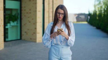 Gözlüklü bir iş kadını akıllı bir telefona yüzünde bir gülümsemeyle bir mesaj yazar. Genç bir kadın telefonu tutuyor ve aktif olarak sosyal ağlardan iletişim kuruyor..
