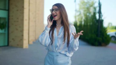 Telefondaki gülümseyen kadın, açık mavi kıyafetli, şehir arkaplanı. Şehir manzarasında açık mavi renkli bir giysi ile neşeli bir sohbet başlar. Çizgili bluz, mutlu bir ifade, telefonda modern bir kadın.