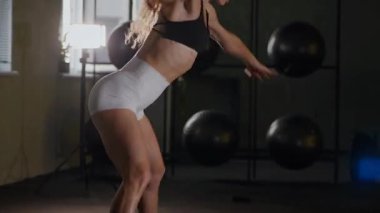 Güzel vücutlu bir kadın spor salonunda ısınıyor ve esniyor. Siyah bluzlu güzel bir sporcu pilates ve spor yapıyor..