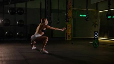 Güzel vücutlu bir kadın spor salonunda ısınıyor ve esniyor. Siyah bluzlu güzel bir sporcu pilates ve spor yapıyor..