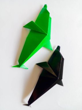 Siyah ve yeşil yunuslar origami beyaz arka planda izole edilmiştir..