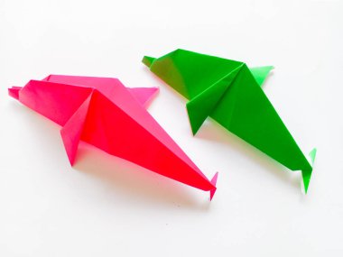 Pembe ve yeşil yunus origamisi beyaz arkaplanda izole edilmiştir..