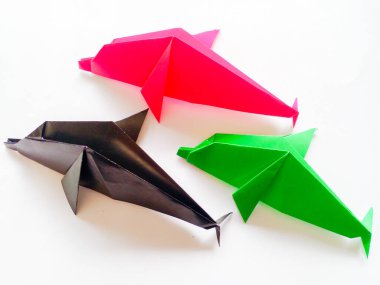 Siyah, pembe ve yeşil yunuslar origami beyaz arka planda izole edilmiştir..