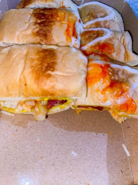 Roti John lezzetli bir Malezya sandviçi körili omlet ile doldurulmuş ve malzemelerle doldurulmuş. Kahverengi bir kutuda Roti John.