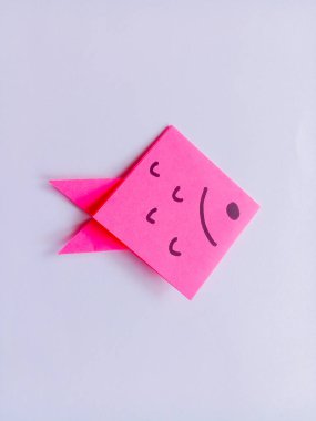Beyaz arkaplanda izole edilmiş pembe balık origamisi.