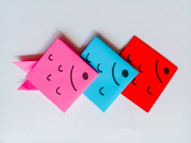 Beyaz arkaplanda pembe, mavi ve kırmızı balık origamisi izole edilmiş..