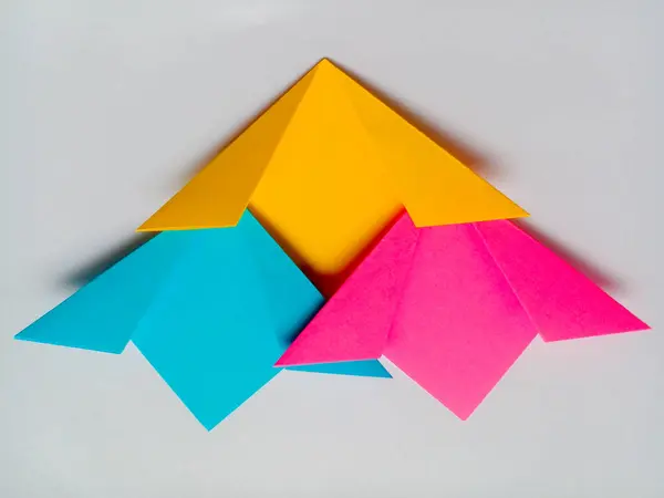 Origami mavi, sarı ve pembe çiçekler beyaz arkaplanda izole edilmiş.