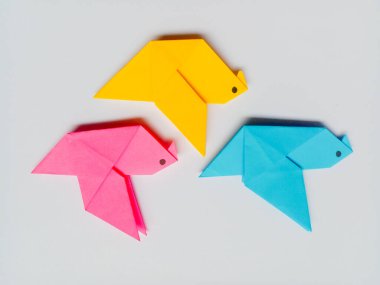 Beyaz arkaplanda pembe, sarı ve mavi origami izole edilmiş..