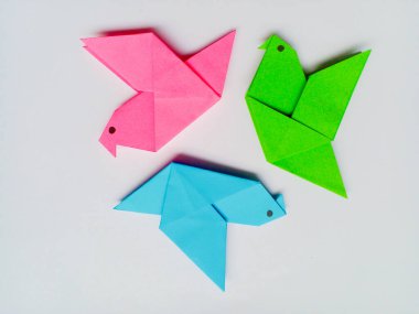 Beyaz arkaplanda pembe, mavi ve yeşil origami izole edilmiş..