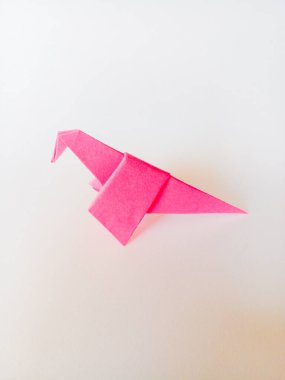 Beyaz arkaplanda izole edilmiş pembe dinozor origamisi.