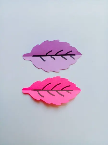 Origami mor ve pembe yapraklar beyaz arkaplanda izole edilmiş.
