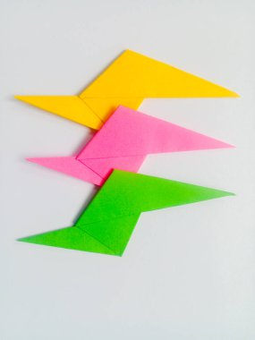 Beyaz arkaplanda yeşil, pembe ve sarı yıldırım origamisi izole.