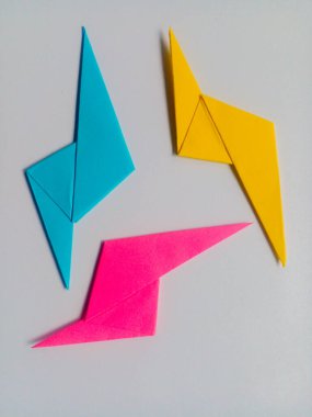 Beyaz arkaplanda mavi, pembe ve sarı yıldırım origamisi izole.
