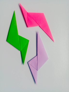 Beyaz arkaplanda yeşil, pembe ve mor yıldırım origamisi izole.