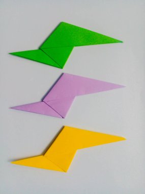 Beyaz arkaplanda yeşil, mor ve sarı yıldırım origamisi izole.