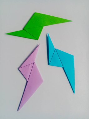 Beyaz arkaplanda yeşil, mor ve mavi yıldırım origamisi izole.