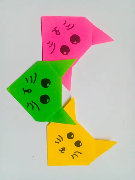 Origami pembe, yeşil ve sarı kedi kafası beyaz arka planda izole edilmiş..