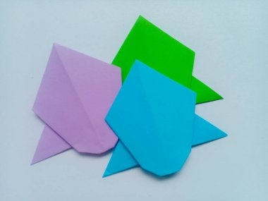 Mor, mavi ve yeşil uçak origamisi beyaz arkaplanda izole edildi.