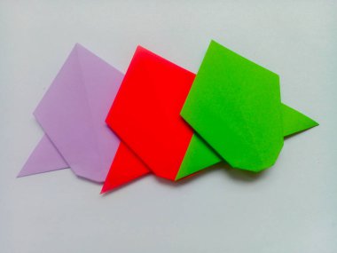 Mor, kırmızı ve yeşil uçak origamisi beyaz arkaplanda izole edildi.
