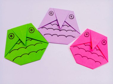 Beyaz arkaplanda yeşil, mor ve pembe baykuş origamisi izole edildi.