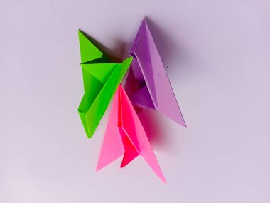 Beyaz arkaplanda yeşil, pembe ve mor düzlem origamisi.
