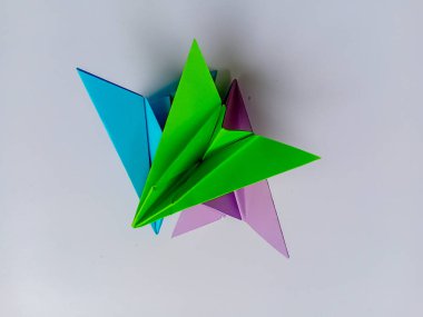 Beyaz arkaplanda yeşil, mavi ve mor düzlem origamisi.