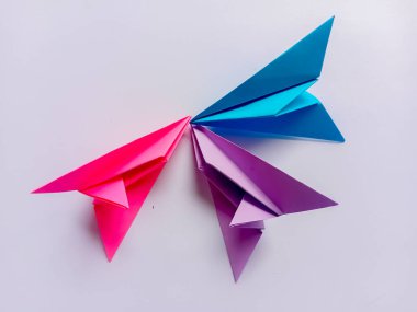 Beyaz arkaplanda pembe, mor ve mavi düzlem origamisi.
