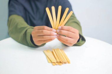 Çocuğun elleri masaya dondurma çubukları koyuyor..