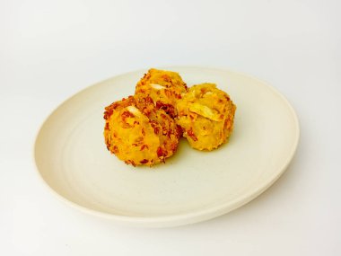 Beyaz arka planda izole edilmiş yuvarlak bir tabakta servis edilen Bala-Bala veya sebzeli börek.