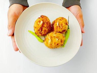 Elinde bir tabak Bala-Bala ya da biberli sebzeli börek, beyaz arka planda izole edilmiş..