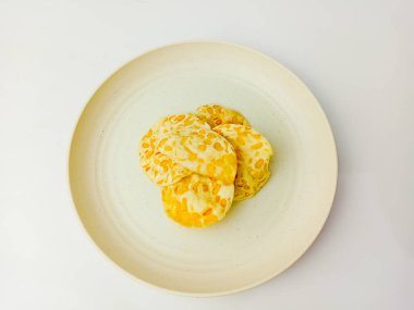 Keripik Tempe ya da Tempeh Chips yuvarlak bir tabakta, beyaz arka planda izole edilmiş. Geleneksel Endonezya yemekleri soya fasulyesi ve pirinç unuyla karıştırılıp ince dilimlenir..