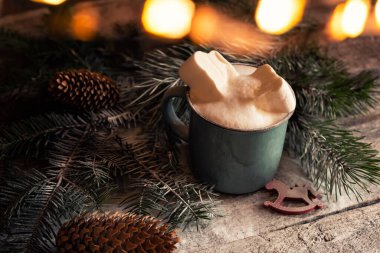 Kış akşamı şenliği hala devam ediyor. Noel kış arkaplanı. Marşmelovlu kakao ve sihirli ışıkları olan Noel ağacı dalları. Siyah fotoğraf.