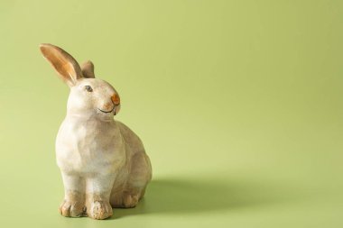 Yeşil arkaplanda tavşan heykeli.