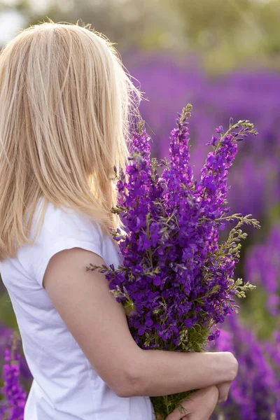 girl in a flowering lilac field with a bouquet