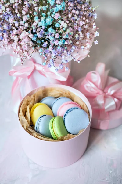 delicate bouquet with pink small flowers and a box of colorful macaroons