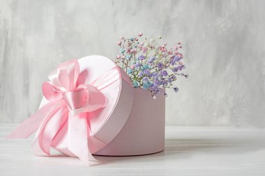  Hafif arka planda, karton bir kutuda pembe küçük çiçekler olan narin bir buket.