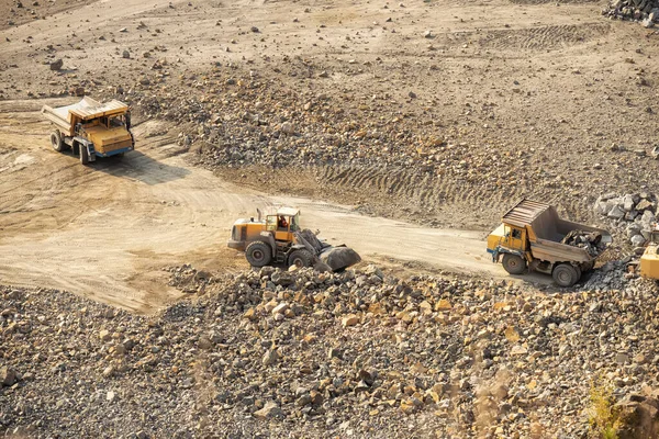 excavators and trucks work in a stone quarry