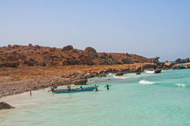 Güneşli bir günde, ıssız bir sahilde zümrüt suyla balıkçı tekneleri ve balıkçılar. Hint Okyanusu 'ndaki Socotra Adası.