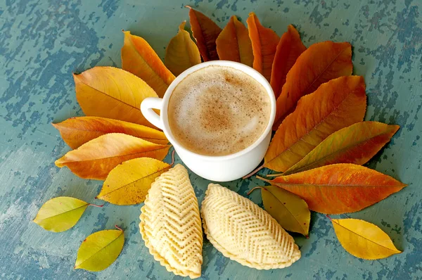 A cup of coffee and autumn leaves on a blue wooden rough background. Autumn mood. Azerbaijani national pastry Shekerbura is Azerbaijani. Traditional delicacy of Azerbaijani cuisine