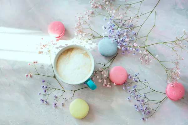 colored macaroon sweets, delicate colored flowers and coffee with milk.