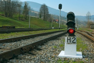 Demiryolu rayları, kırmızı trafik ışıkları ve yeşil dağlar. Tren istasyonu.