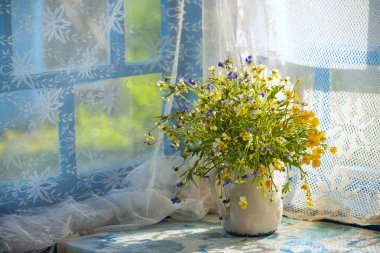 Verandadaki pencerenin yanındaki bidonun içinde güzel bir buket yabani çiçek. Eski köy fotoğrafı..