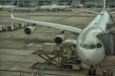 Terminalin yanındaki havaalanında bir yolcu uçağına kargo yükleme işlemi