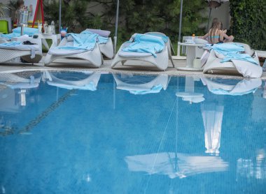 Küçük havuz kenarında rahat bir ortam. Sıralar dolusu güneş ışığı ve havuzun sakin suları..