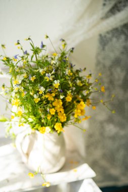 Pencerenin yanındaki parlak odada menekşeli bir buketin hafif fotoğrafı. çok yumuşak seçici odak