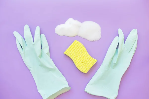 Cleaning supplies - rubber gloves, sponge and cleaning agent on a lilac background. Flat lay, top view, copy space